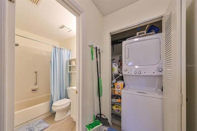 clothes washing area with hardwood / wood-style floors and stacked washing maching and dryer