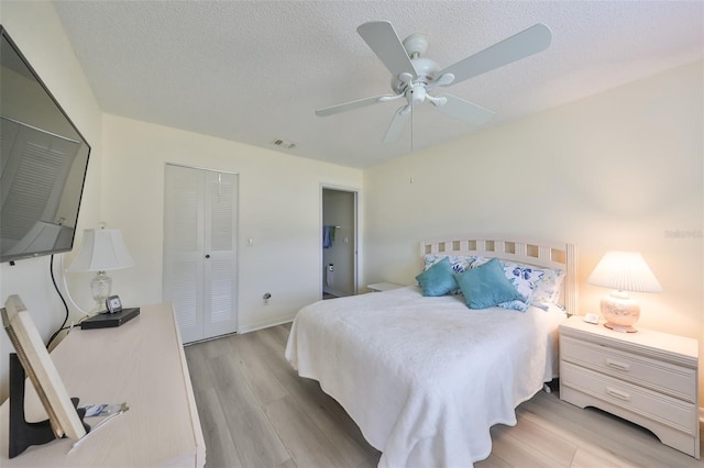 bedroom featuring a closet, ceiling fan, light hardwood / wood-style flooring, and a textured ceiling