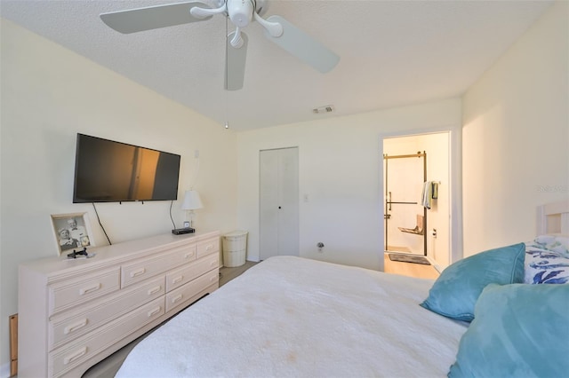 bedroom with ensuite bath, ceiling fan, wood-type flooring, a textured ceiling, and a closet