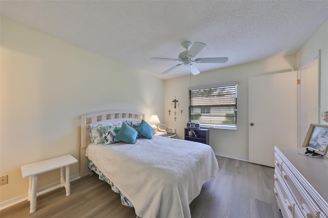 bedroom with ceiling fan, wood-type flooring, and a textured ceiling