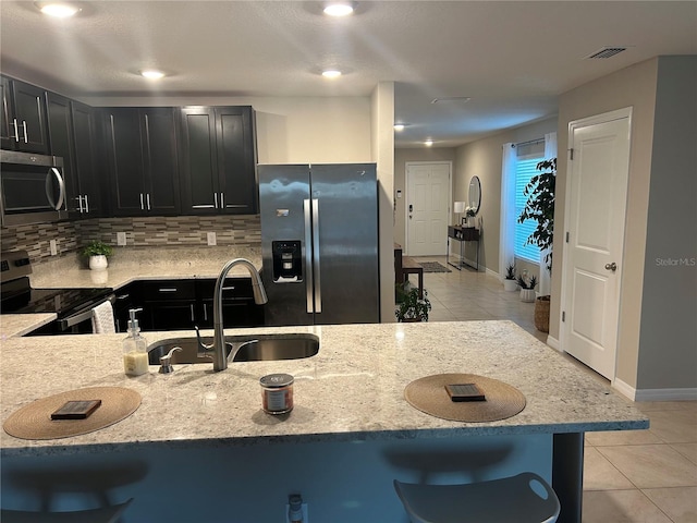 kitchen featuring a kitchen bar, decorative backsplash, stainless steel appliances, and sink