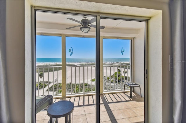 sunroom with a view of the beach, ceiling fan, and a water view