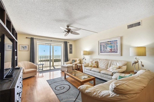 living room featuring ceiling fan, hardwood / wood-style floors, and a textured ceiling