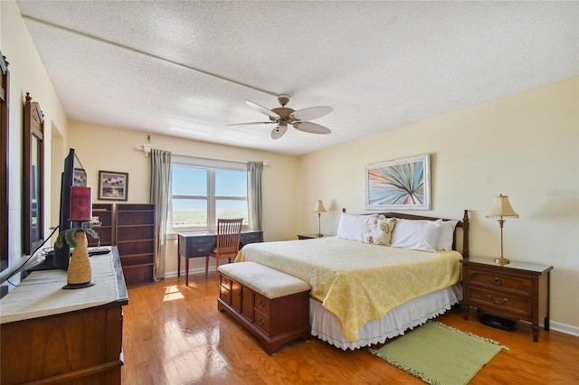 bedroom featuring hardwood / wood-style flooring, ceiling fan, and a textured ceiling