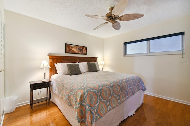 bedroom with a textured ceiling, wood-type flooring, and ceiling fan