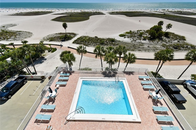 view of swimming pool with a water view and a beach view