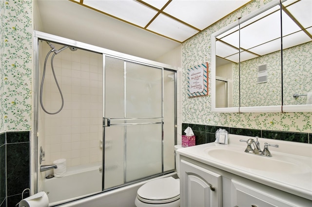 full bathroom featuring toilet, vanity, and bath / shower combo with glass door