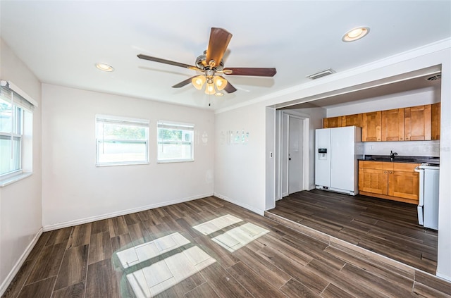 kitchen with a wealth of natural light, dark hardwood / wood-style flooring, crown molding, and white appliances