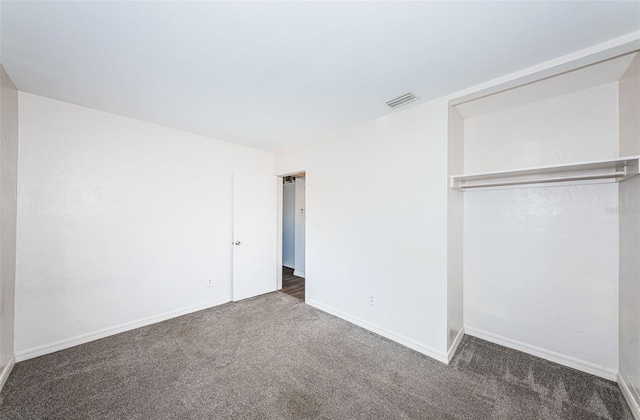 unfurnished bedroom with dark colored carpet and a closet