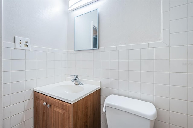 bathroom with vanity, toilet, and tile walls