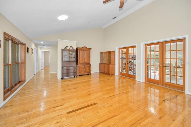 unfurnished room with ceiling fan, high vaulted ceiling, light hardwood / wood-style floors, and french doors