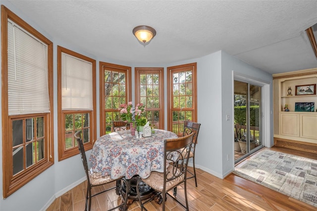 dining space featuring light wood-type flooring and a textured ceiling