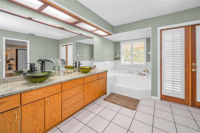 bathroom featuring tiled tub, vanity, and tile patterned floors