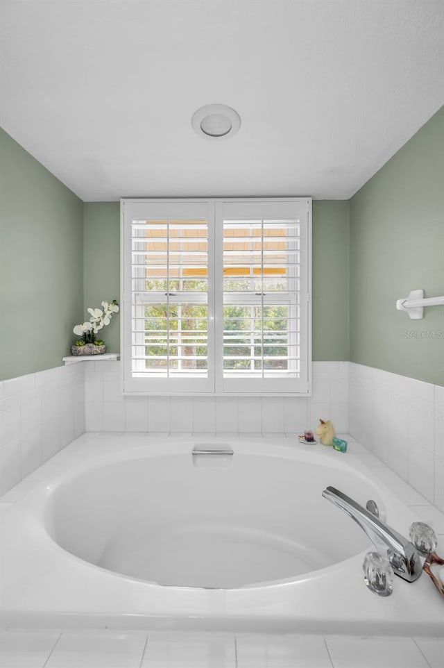 bathroom featuring a relaxing tiled tub and a healthy amount of sunlight