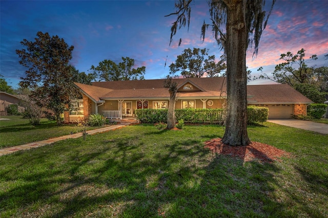 ranch-style house with a yard, a garage, covered porch, and concrete driveway