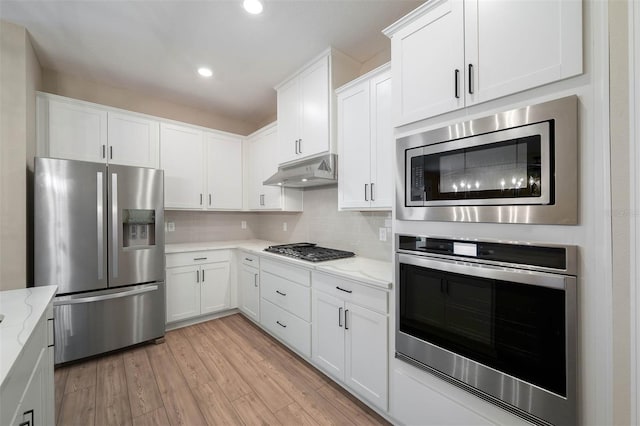7865 Somersworth Dr, Kissimmee, FL 34747 - kitchen with stainless steel appliances, under cabinet range hood, light stone countertops, white cabinets, and recessed lighting