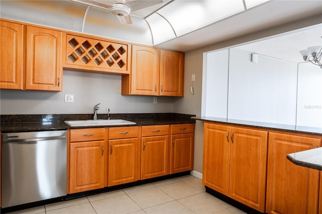 kitchen with stainless steel dishwasher, ceiling fan, sink, light tile patterned floors, and dark stone countertops