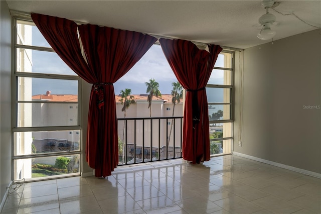 spare room with ceiling fan and a wall of windows