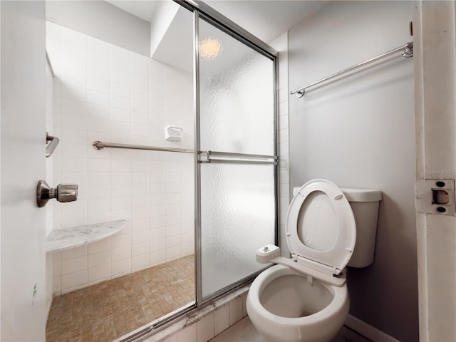 bathroom featuring toilet and a shower with shower door