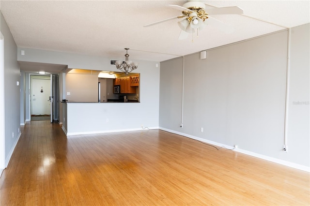 unfurnished living room featuring light hardwood / wood-style flooring, ceiling fan with notable chandelier, and a textured ceiling