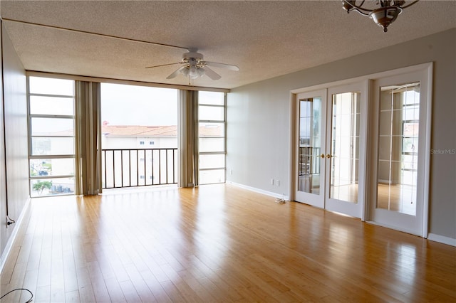 empty room with ceiling fan, french doors, light hardwood / wood-style floors, and a textured ceiling