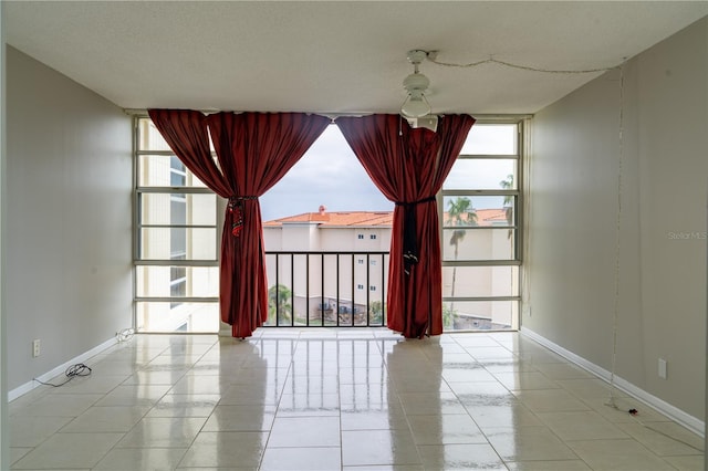 spare room with ceiling fan, floor to ceiling windows, and a textured ceiling