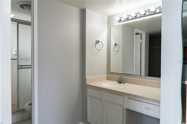 bathroom with toilet, vanity, and walk in shower