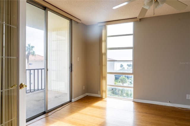 spare room with a textured ceiling, floor to ceiling windows, a healthy amount of sunlight, and ceiling fan