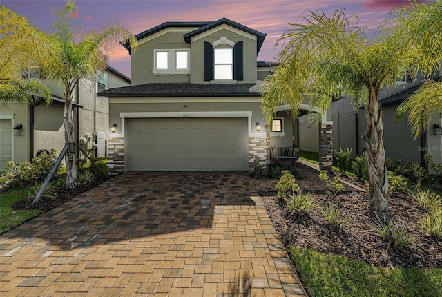 view of front of property with decorative driveway, stone siding, and stucco siding