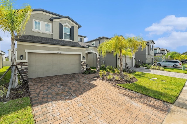 view of front of home with stone siding, decorative driveway, and stucco siding