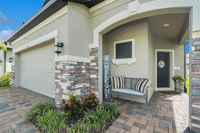 entrance to property featuring stone siding, an attached garage, and stucco siding