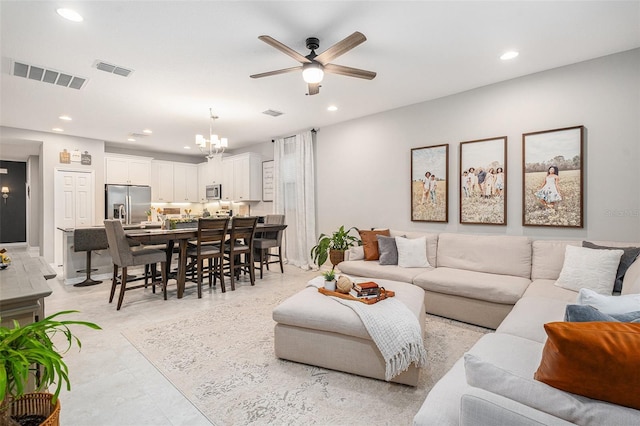 tiled living room with ceiling fan with notable chandelier