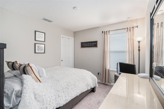 bedroom featuring carpet floors, visible vents, and a textured ceiling