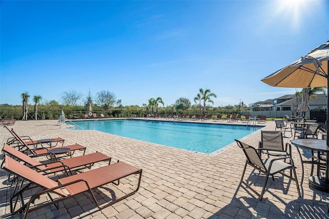 pool with a patio area and fence