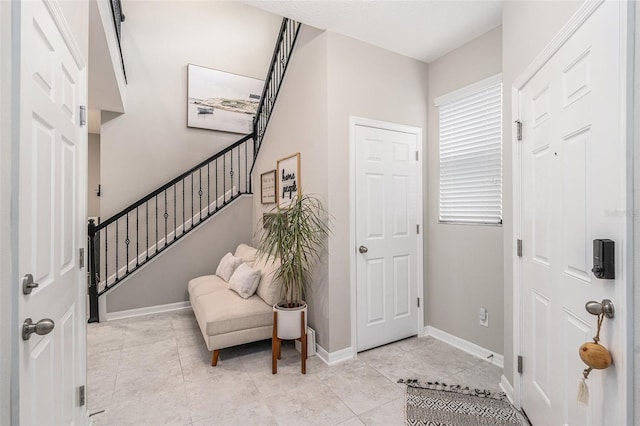 entrance foyer with stairs, light tile patterned floors, and baseboards