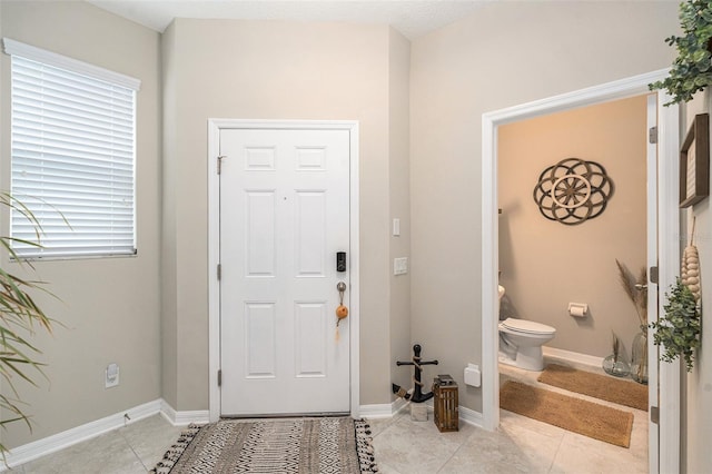 entryway with light tile patterned flooring and baseboards