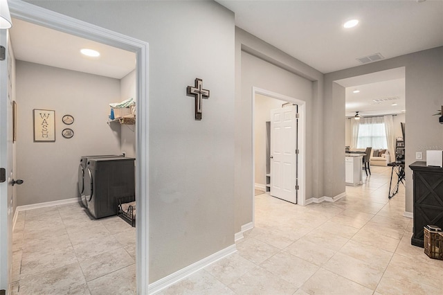 hallway with light tile patterned floors, washing machine and dryer, visible vents, and baseboards