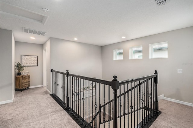 hall with carpet, an upstairs landing, visible vents, and baseboards