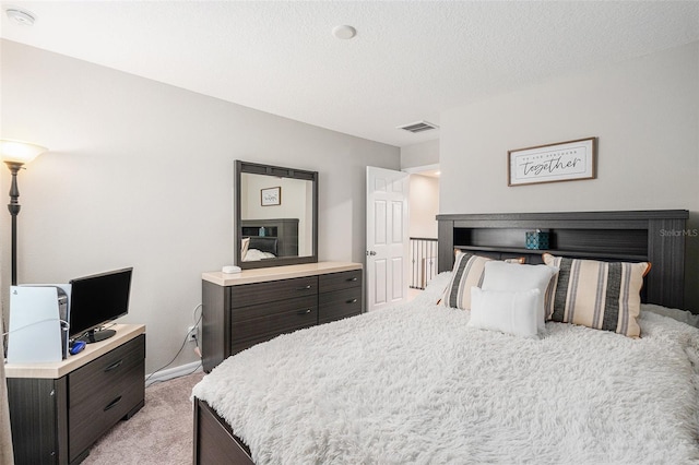 bedroom featuring visible vents, a textured ceiling, and light colored carpet