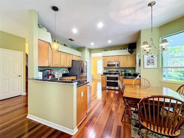 kitchen featuring hanging light fixtures, decorative backsplash, a notable chandelier, kitchen peninsula, and stainless steel appliances