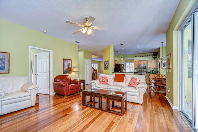 living room featuring ceiling fan, a textured ceiling, and light hardwood / wood-style flooring