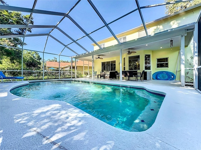 view of pool featuring a patio, glass enclosure, and ceiling fan