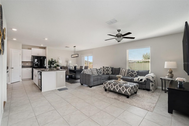 tiled living room featuring ceiling fan, a healthy amount of sunlight, and sink