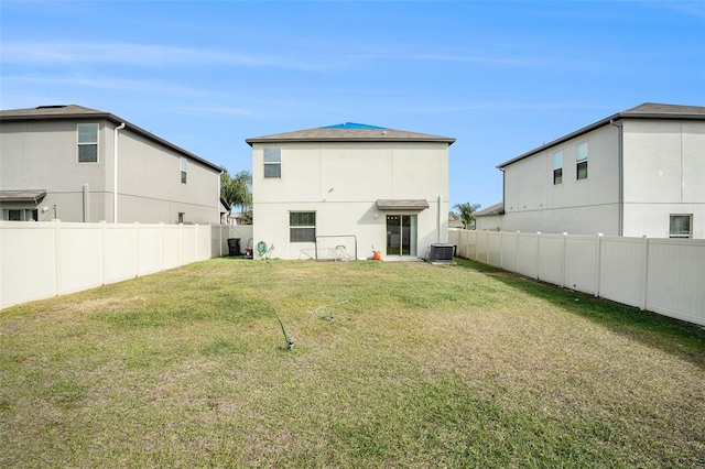 rear view of house featuring central air condition unit and a yard