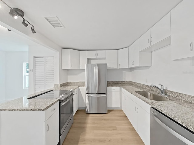 kitchen with sink, light wood-type flooring, light stone counters, white cabinetry, and stainless steel appliances