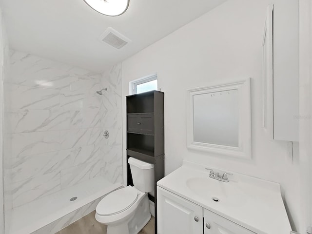 bathroom featuring hardwood / wood-style flooring, vanity, toilet, and a tile shower