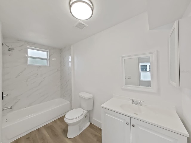 full bathroom with tiled shower / bath combo, toilet, wood-type flooring, and vanity