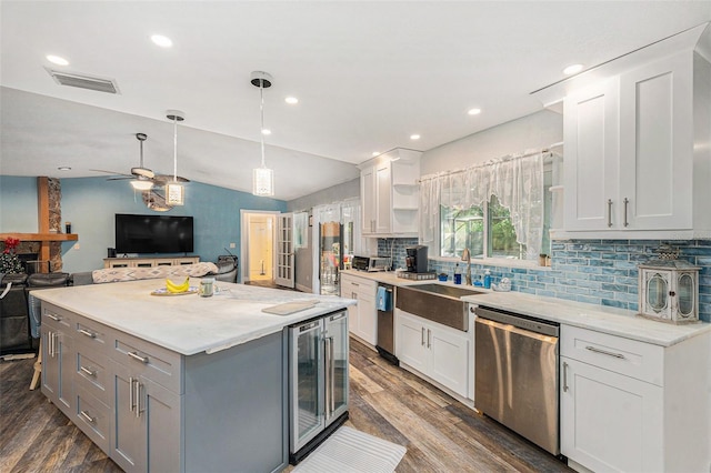 kitchen featuring tasteful backsplash, stainless steel dishwasher, vaulted ceiling, beverage cooler, and white cabinets