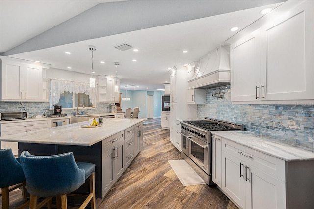 kitchen with white cabinets, pendant lighting, double oven range, and premium range hood