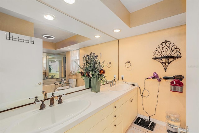 bathroom featuring tile patterned floors, vanity, a tray ceiling, and toilet